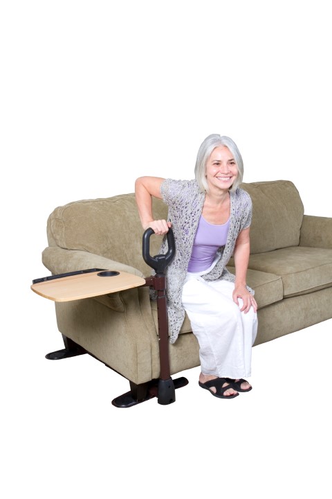 Frau benutzt Sofagriff um von Couch aufzustehen